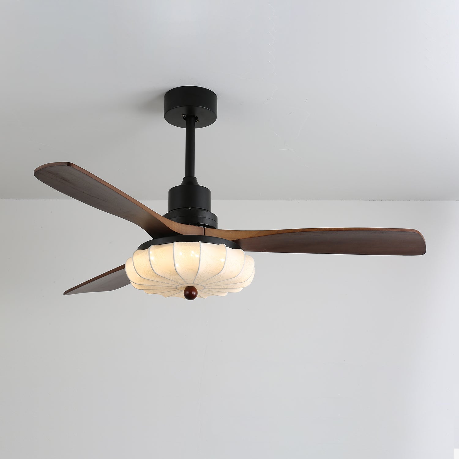 Vue rapprochée des pales en bois et de l'abat-jour en verre du plafonnier ventilateur Ventra.