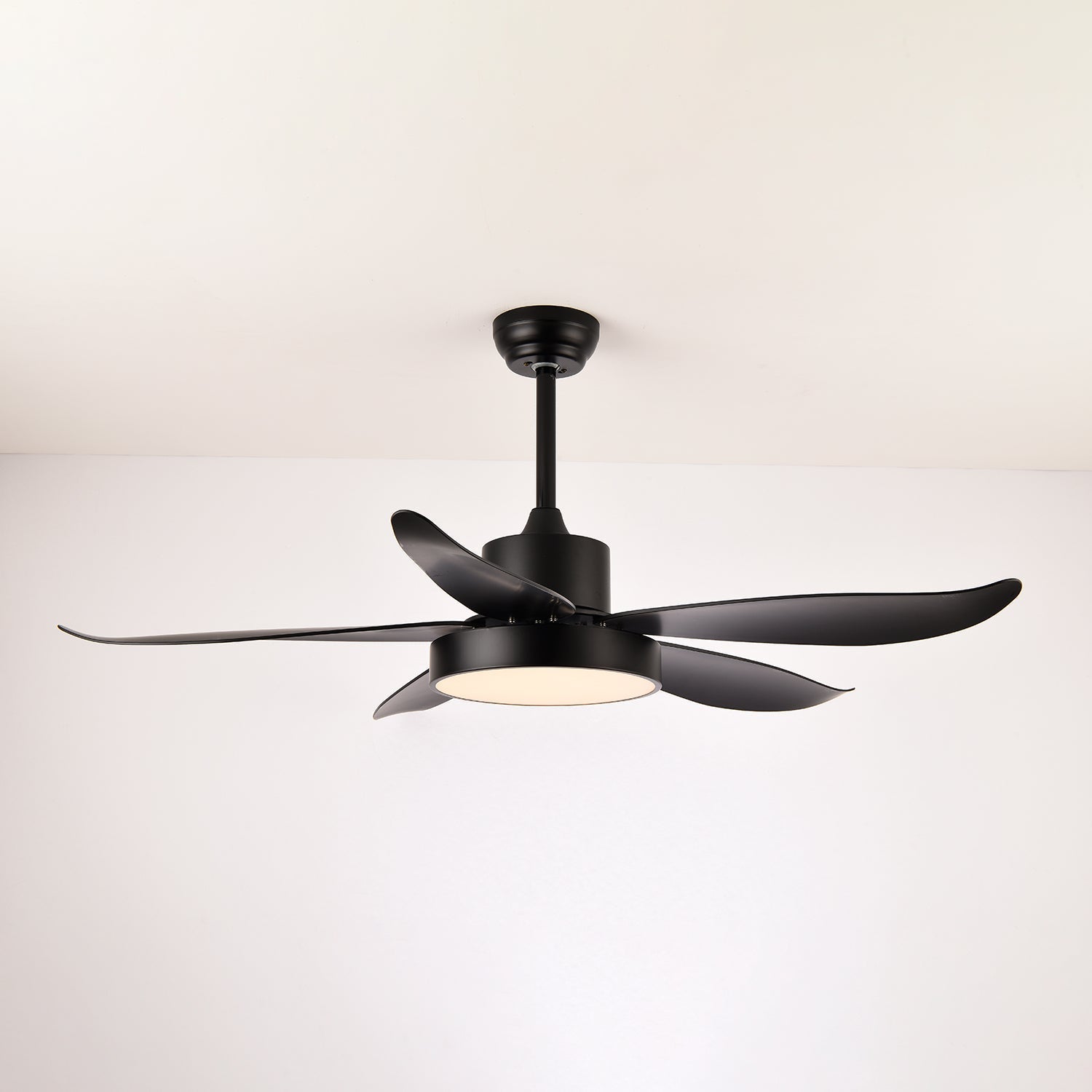 Gros plan sur le cadre métallique noir et les pales en plastique du ventilateur de plafond.